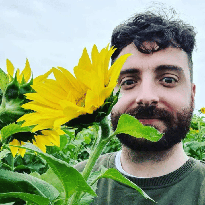 ACA apprentice beside a giant sunflower