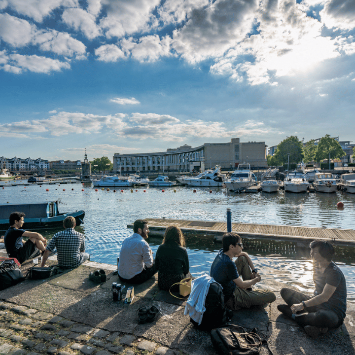Small groups of people socialising at Bristol Harbour on a summer evening