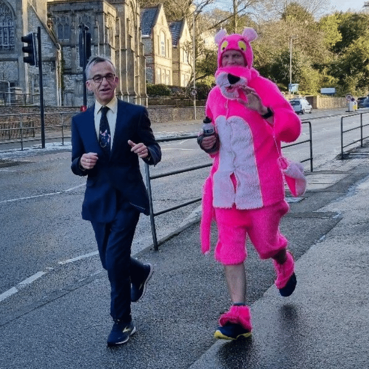 Two colleagues taking part in a fun run, one dressed in a suit and another as a pink panther