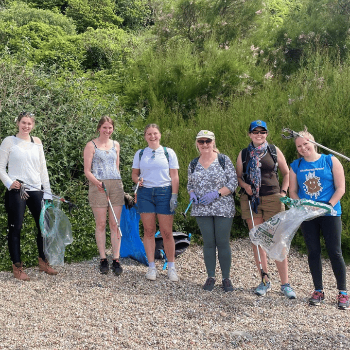 Group of colleagues participating in a beach clean on a pebble beach together for a volunteering day