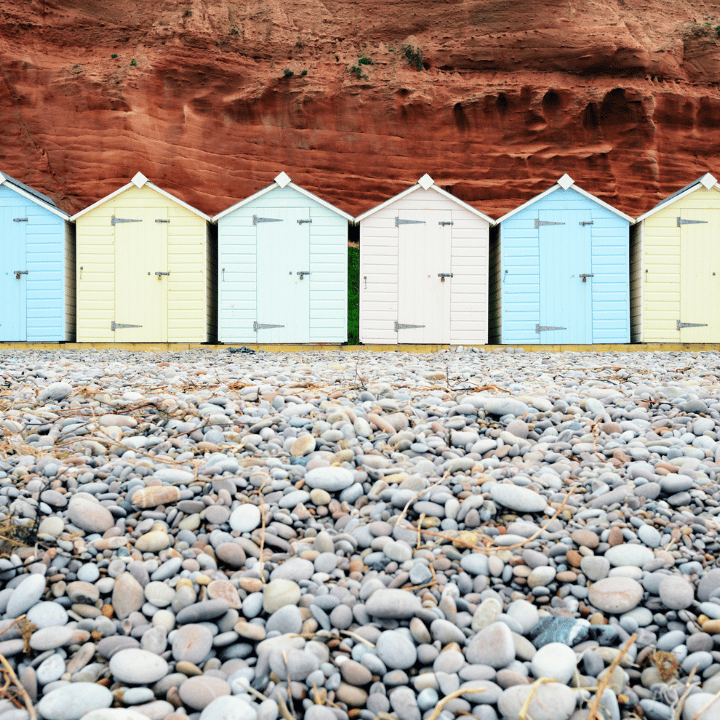 Pastel coloured beach huts on a pebble beach in Devon