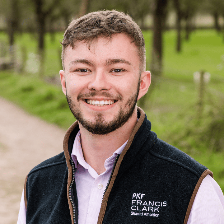 Young professional standing in a rural setting wearing a branded gilet