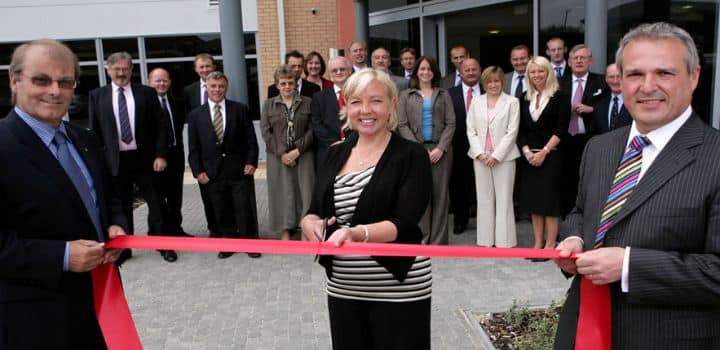 Deborah Meaden cutting the ribbon at office opening with smiling staff around her