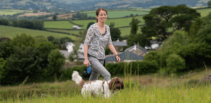 Woman enjoying a walk with her dog in the countryside whilst working from home
