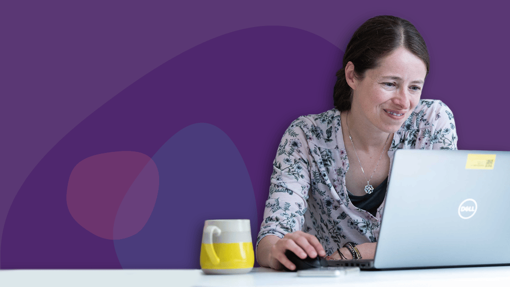 Woman working at home, sits behind her laptop and a bright mug beside it
