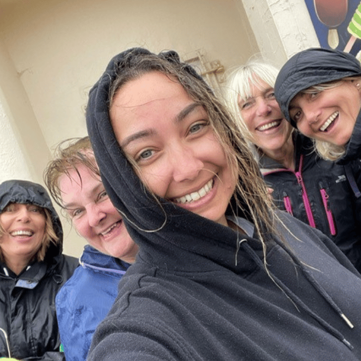Group of colleagues laughing outside on a volunteering day during rainy weather