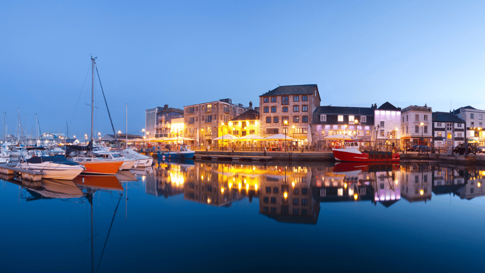 Sutton Harbour in Plymouth at twilight with restaurants lit up