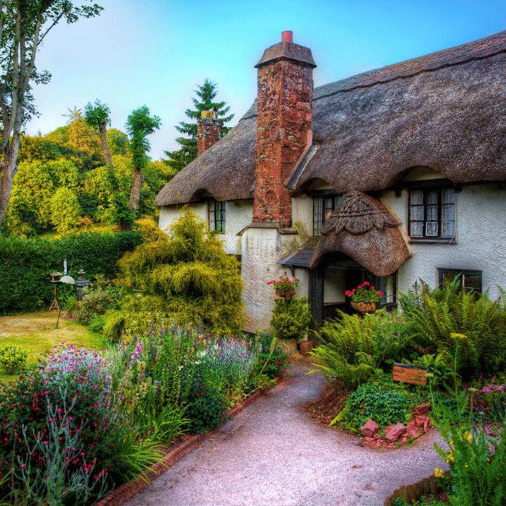 Traditional cottage with thatched roof and colourful garden at Cockington, Torquay