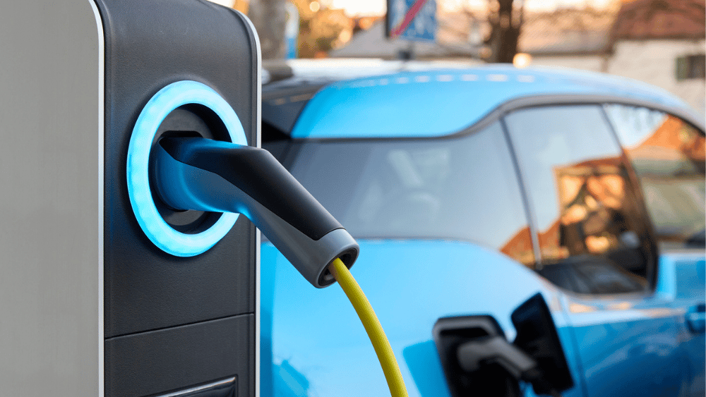Electric charging point with blue car in the background