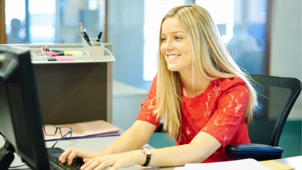 A happy young woman working on a computer in an office