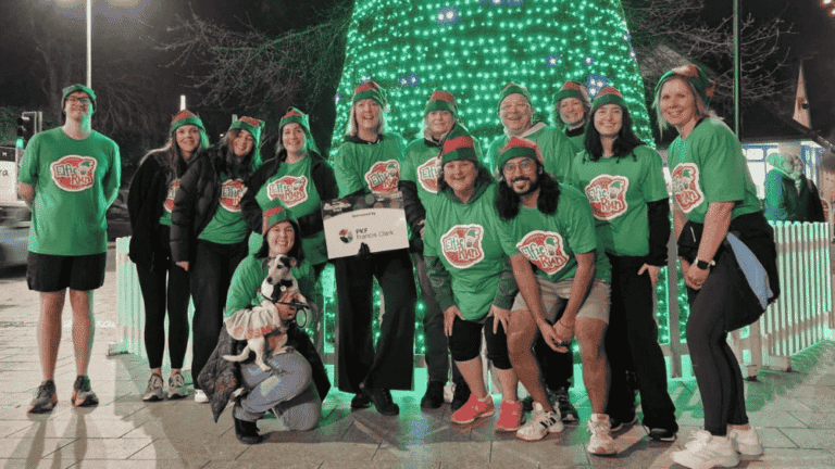 Torquay team take on the Elfie run fundraiser - in matching running tops in front of a Christmas tree